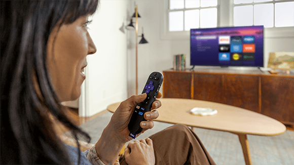 Persona utilizando el Roku Voice Remote con el Roku Streaming Stick Plus para controlar la TV