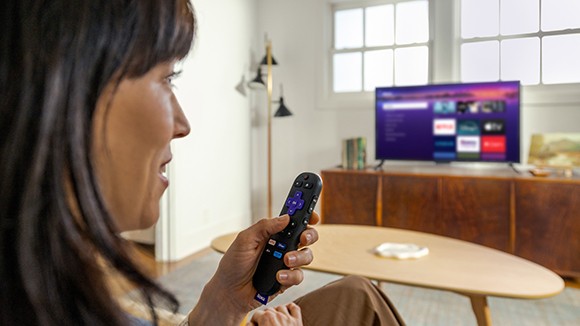 Person using the Roku Voice Remote with the Roku Streaming Stick Plus to control their TV