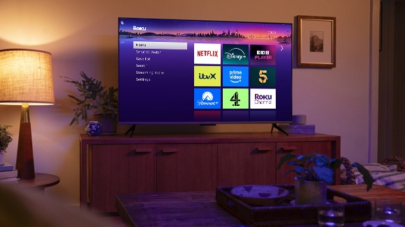 Person using a Roku remote to control their Roku streaming device on a TV displaying a 4K picture