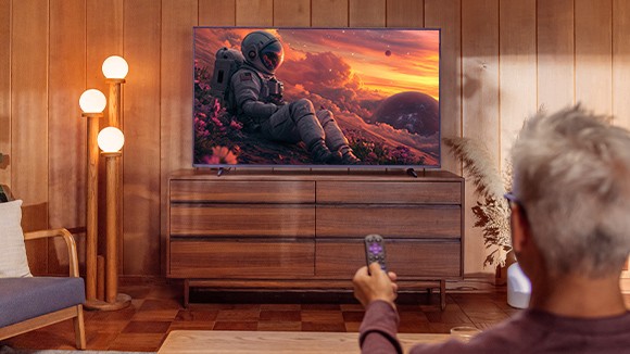 Person using a remote with the Roku Streaming Stick Plus to stream a movie on their TV
