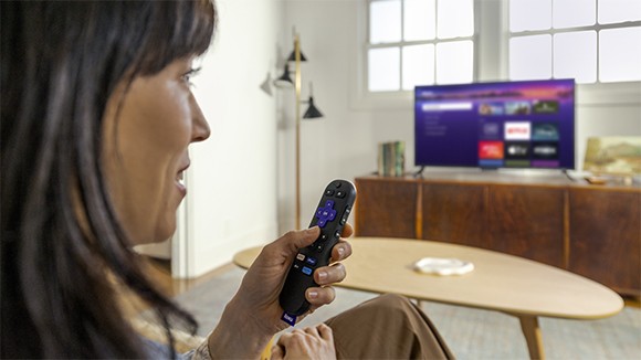 Pessoa usando o Roku Voice Remote com o Roku Streaming Stick Plus para controlar a TV