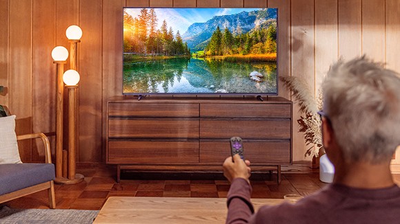 Person using a Roku remote to control their Roku streaming device on a TV displaying a 4K picture