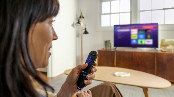 Person using the Roku Voice Remote with the Roku Streaming Stick Plus to control their TV