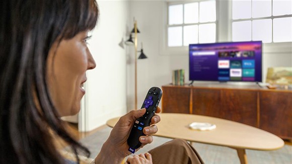 Personne utilisant la télécommande vocale Roku avec la Clé de diffusion en continu Roku Plus pour contrôler son téléviseur