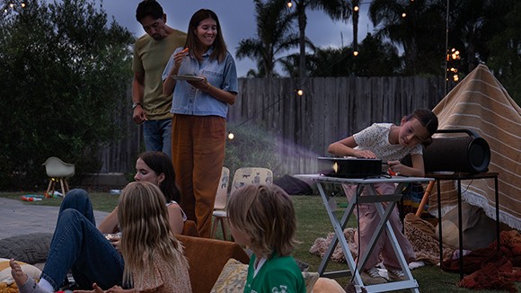 Person in their backyard inserting the Roku Streaming Stick 4K into a projector