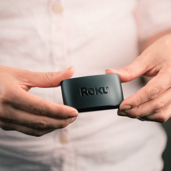 Close-up image of a person holding a Roku Express