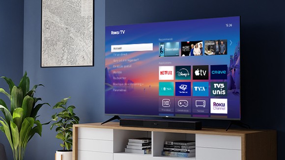 Téléviseur 4K Série Select Roku et barre de son sans fil Roku TV posés sur un meuble bas
