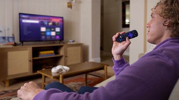Person using the Roku Voice Remote to control their Roku TV