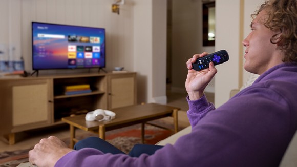 Person using the Roku Voice Remote to control their Roku TV