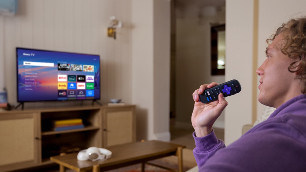 Person using the Roku Voice Remote to control their Roku TV