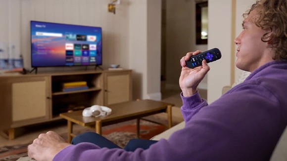 Personne utilisant la télécommande vocale Roku pour contrôler sa Roku TV